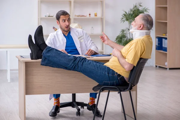 Yaşlı boynu yaralı bir adam genç erkek doktoru ziyaret ediyor. — Stok fotoğraf