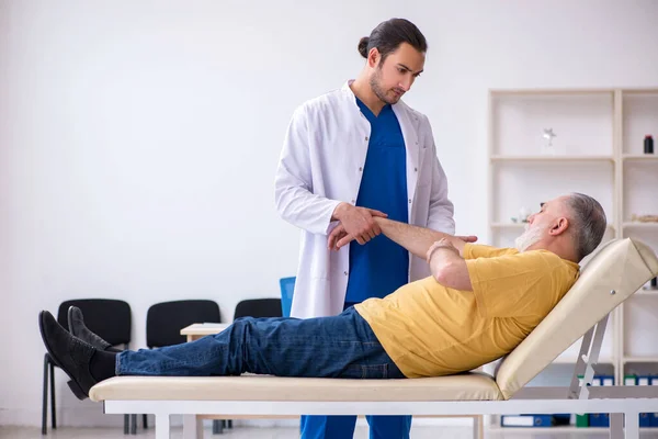 Alter verletzter Mann besucht jungen Arzt — Stockfoto