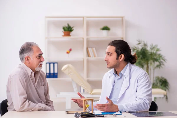 Oude mannelijke patiënt op bezoek bij jonge arts in time management concep — Stockfoto