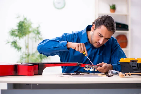 Jovem reparador do sexo masculino reparando guitarra — Fotografia de Stock