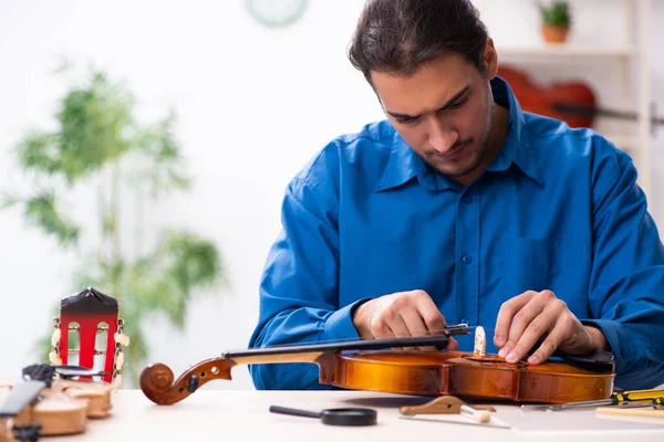 Jonge mannelijke reparateur die viool repareert — Stockfoto