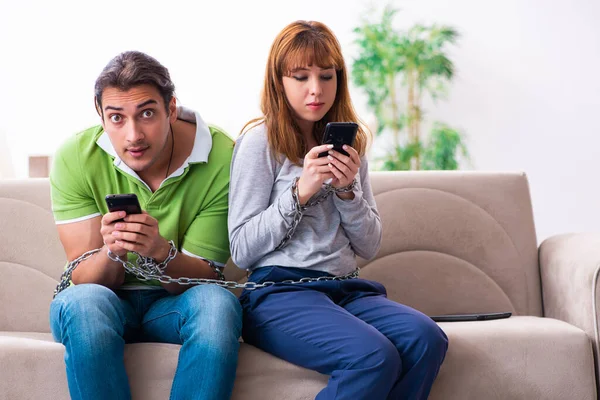 Pareja joven en concepto de dependencia gadget — Foto de Stock