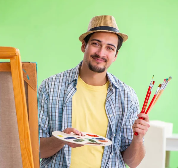 Young male artist working on new painting in his studio