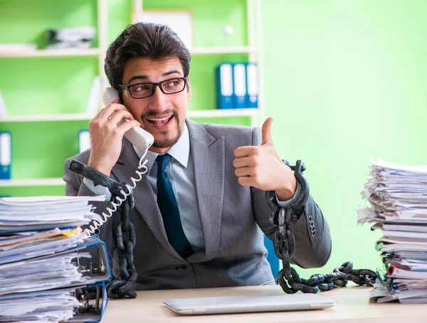 Empregado acorrentado à sua mesa devido à carga de trabalho — Fotografia de Stock