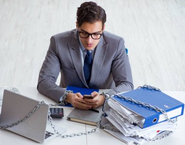 Ofis masasına zincirlenmiş meşgul bir çalışan.