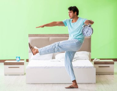 Pijamalı genç adam sabah egzersizi yapıyor.