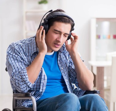 Tekerlekli sandalyede müzik dinleyen engelli adam.