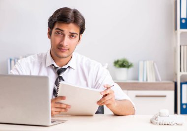 Genç yakışıklı işadamı ofiste çalışıyor.