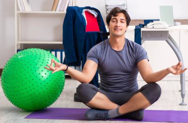 Ofiste egzersiz yapan genç bir erkek.