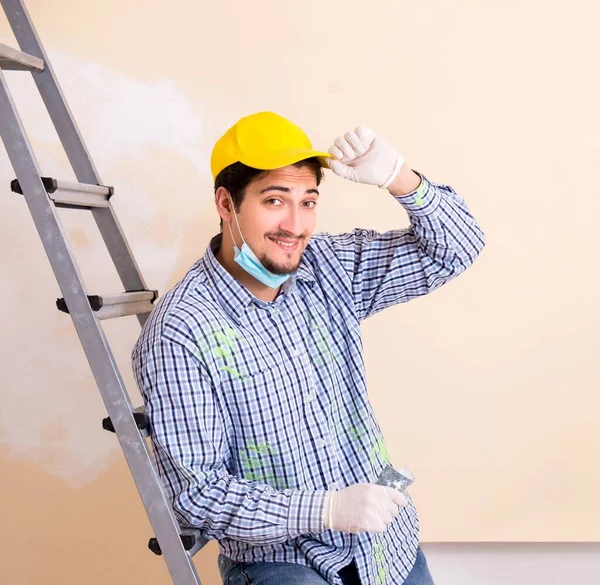 Fiatal vállalkozó csiszoló fal le csiszolópapírral — Stock Fotó