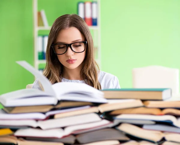 Jovem estudante se preparando para exames com muitos livros — Fotografia de Stock