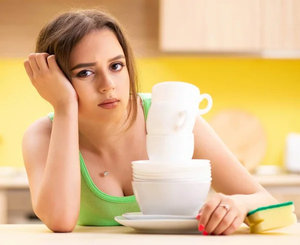 Молода жінка прибирає і миє посуд на кухні — стокове фото