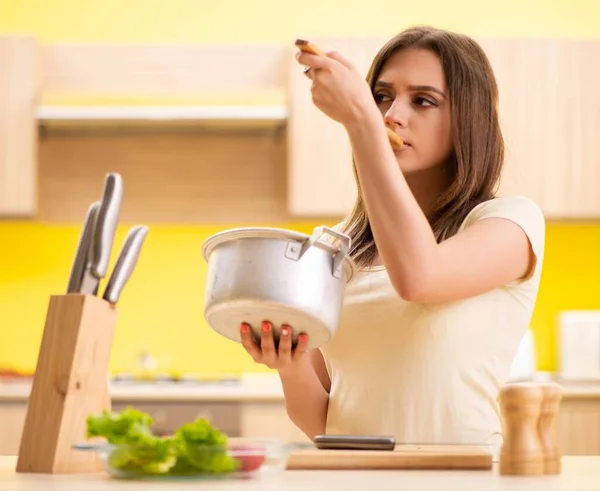 Jonge vrouw koken soep in keuken thuis — Stockfoto