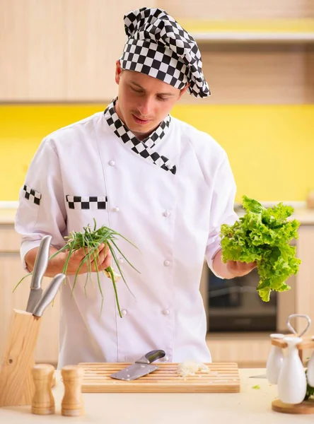 Joven cocinero profesional preparando ensalada en la cocina — Foto de Stock