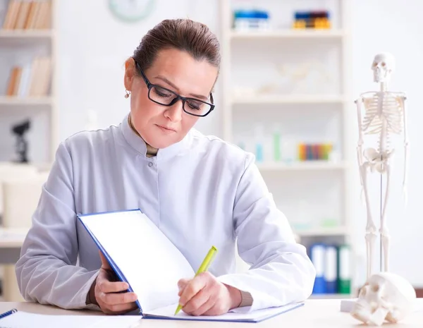 Woman doctor studying human skeleton