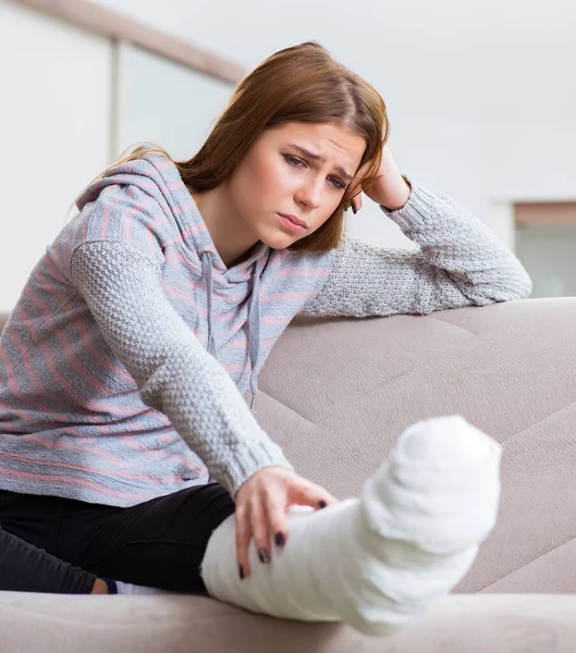 Mujer joven con la pierna rota en casa — Foto de Stock