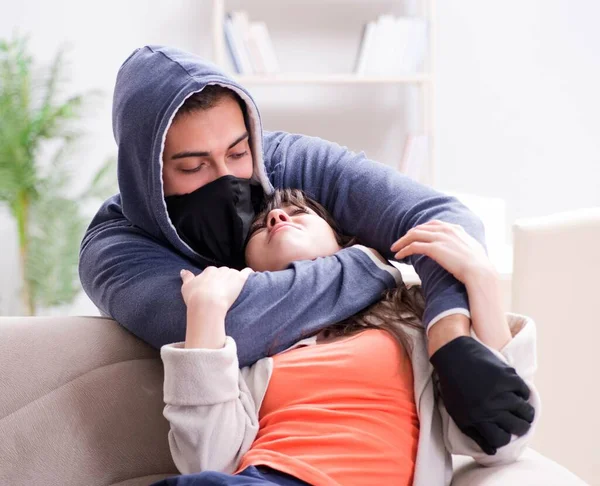 Silahlı bir adam evde genç bir kadına saldırıyor.