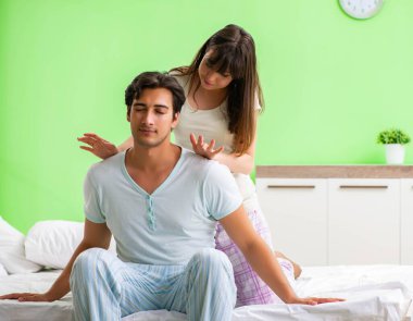 Yatak odasında kocasına masaj yapan bir kadın.