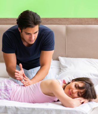 Adam yatak odasında karısına masaj yapıyor.
