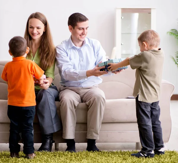 Padres jóvenes repartiendo regalos de Navidad en casa — Foto de Stock