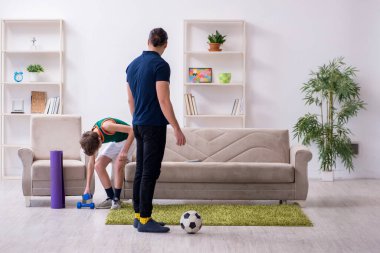 Baba ve oğul içeride spor yapıyor.
