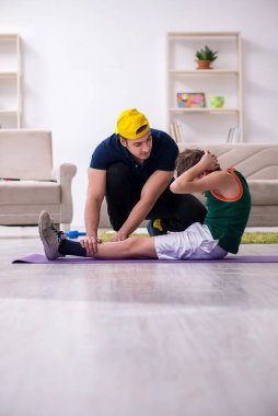 Baba ve oğul içeride spor yapıyor.