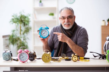 Atölyede çalışan yaşlı bir erkek saatçi.