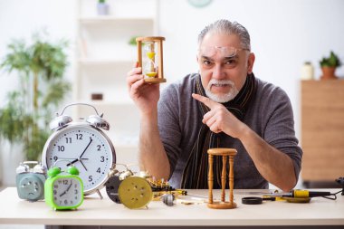 Atölyede çalışan yaşlı bir erkek saatçi.