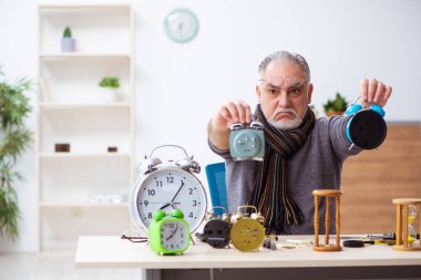 Atölyede çalışan yaşlı bir erkek saatçi.