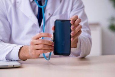 Steteskopu tamir eden genç bir erkek doktor.