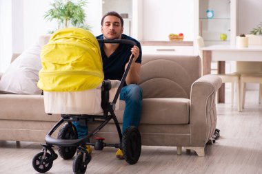 Genç baba yeni doğan bebeğe bakıyor.