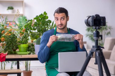 Evin içinde bitkileri olan genç bir erkek bahçıvan.