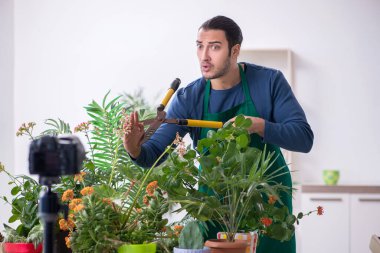 Evin içinde bitkileri olan genç bir erkek bahçıvan.