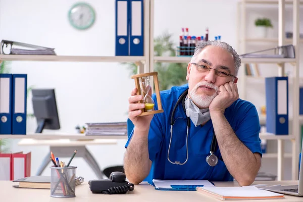 Oude mannelijke arts werkzaam in de kliniek — Stockfoto