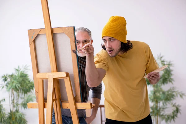 Velho aprendendo com o jovem pintor — Fotografia de Stock