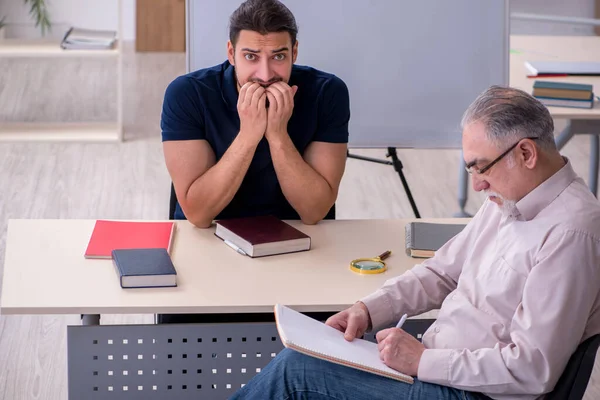 Old teacher and young male student in the classroom — Stock Photo, Image