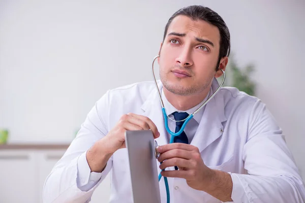 Young male doctor with stethoscope repairing computer — Stock Photo, Image