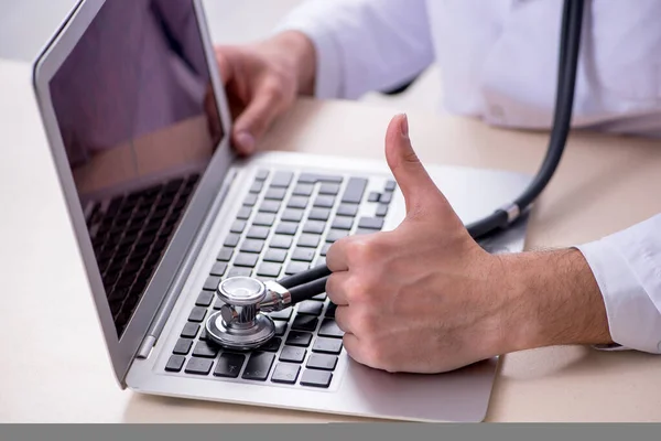 Joven doctor masculino con estetoscopio reparando computadora —  Fotos de Stock