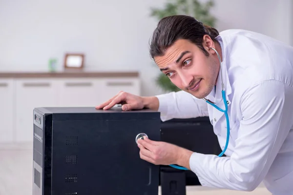 Młody lekarz ze stetoskopem naprawiającym komputer — Zdjęcie stockowe