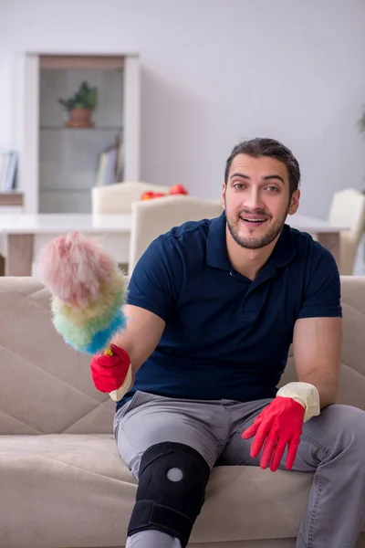 Young leg injured contractor cleaning the house — Stock Photo, Image