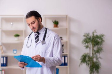 Klinikte çalışan genç erkek doktor.