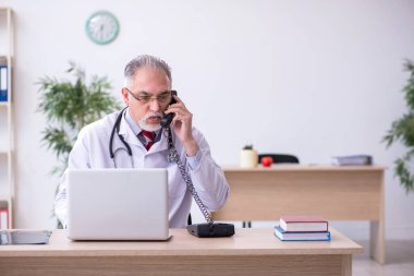 Klinikte çalışan yaşlı erkek doktor.