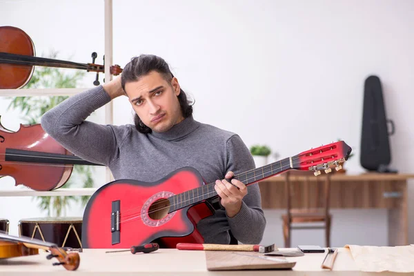 Young male repairman repairing guitar