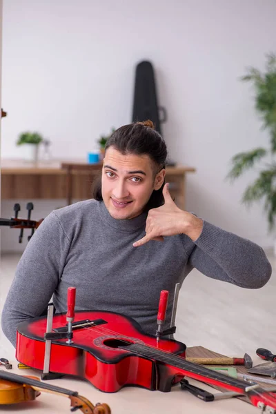 Young male repairman repairing guitar — Stock Photo, Image