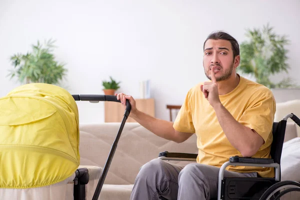 Jongeman aannemer in rolstoel op zoek naar pasgeborene — Stockfoto