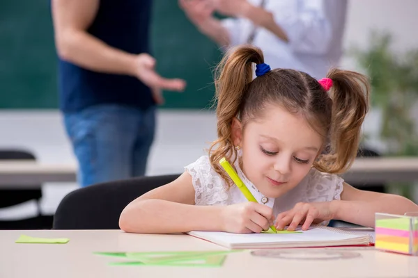 Junge Eltern, alter männlicher Lehrer und kleines Mädchen im Klassenzimmer — Stockfoto