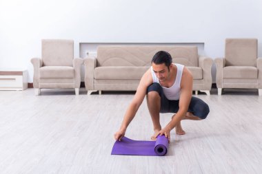 Genç adam evde antrenman ve egzersiz yapıyor.