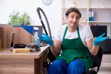 Genç yakışıklı müteahhit ofisi temizliyor.