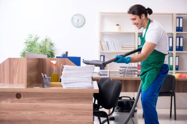 Genç yakışıklı müteahhit ofisi temizliyor.