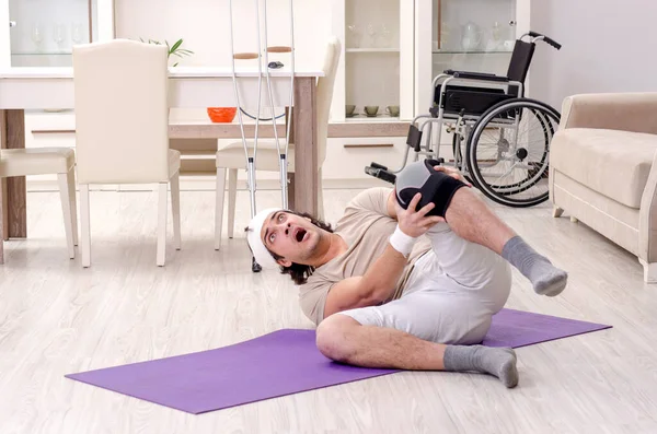 Injured young man doing exercises at home — Stock Photo, Image